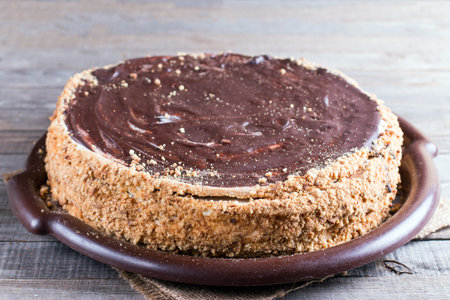 Sweet honey cake on a wooden table with with chocolate icing