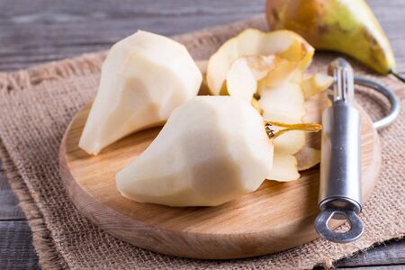 Peeled pears on a cutting board on a tableの写真素材