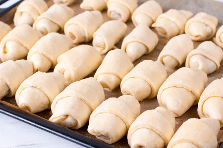 Making small homemade croissants in the kitchen on a baking sheet - a traditional European pastryの写真素材