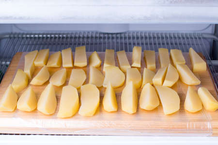 Frozen potatoes on the chopping board in the freezer. Frozen foodの写真素材