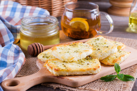 Grilled haloumi cheese with herbs and honey on a cutting boardの写真素材