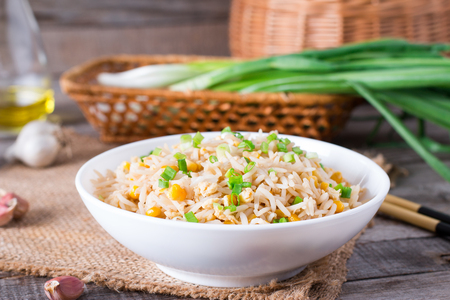 Asian fried rice with eggs and corn on the plate on wooden tableの写真素材