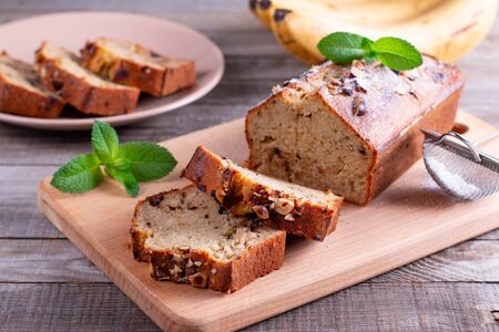 Banana bread with bananas sliced on a cutting board with bananas in backgroundの写真素材