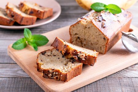 Banana bread with bananas sliced on a cutting board with bananas in backgroundの写真素材