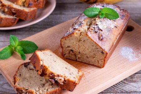 Banana bread with bananas sliced on a cutting board with bananas in backgroundの写真素材