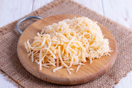 Grated cheese on a wooden cutting board closeup