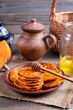 Pumpkin pancakes with honey on a plate on a wooden backgroundの写真素材
