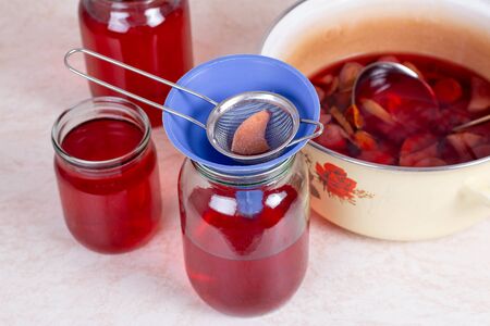 A glass jar with red compote on the kitchen tableの写真素材
