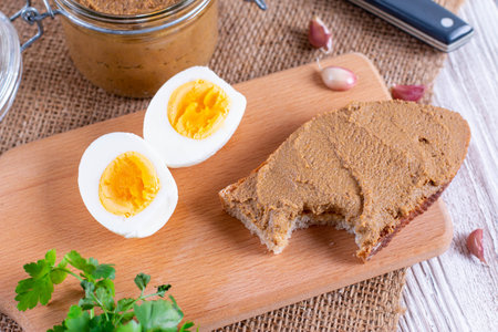Fresh homemade chicken liver pate on bread on wooden background
