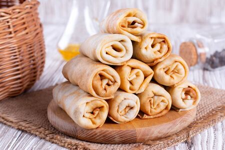 Rolls pancakes stuffed with meat and rice on a wooden cutting boardの写真素材