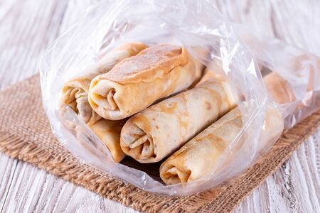 Frozen stuffed pancakes in plastic bags on the tableの写真素材