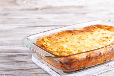 Cottage cheese casserole with raisins in a glass baking dish on a white wooden table