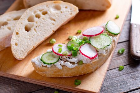 sandwiches with cucumbers, radishes and cream cheese on wooden board, Closeup, Breakfast or lunch conceptの写真素材