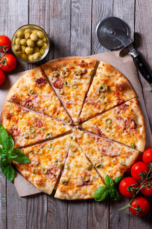 Tasty pizza , top view. Italian pizza with tomato, mozzarella cheese, olives on a wooden tableのeditorial素材