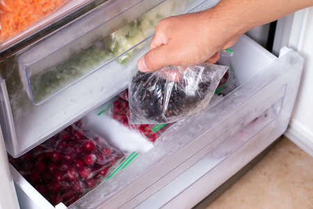 Man taking plastic bag with black currant from refrigerator, closeupの写真素材