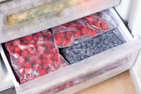 Frozen berries in plastic bags in the freezer. Open deep freeze filled with frozen berriesの写真素材