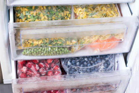 Plastic bags with different frozen vegetables in refrigerator. Vegetables on the freezer shelvesの写真素材