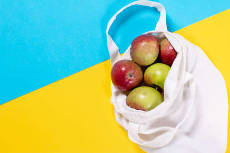 Organic apples in cotton bag on a color background. Flat lay, top view, trendy background.の写真素材