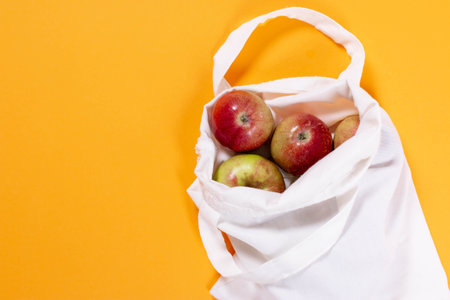 Organic apples in cotton bag on a color background. Flat lay, top view, trendy background.の写真素材