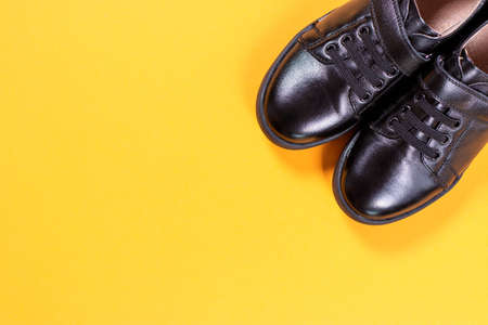 Black shoes on yellow background. Flat lay, top view trendy background. Fashion blog look. Top view. Copy space.の写真素材