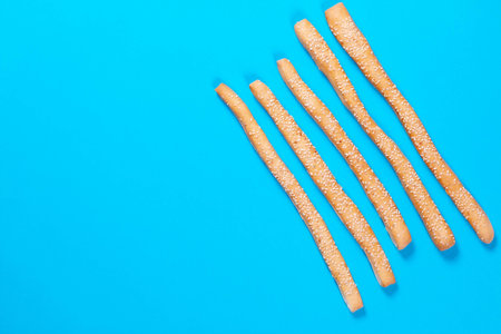 Freshly baked grissini on color background. Flat lay, top view trendy background