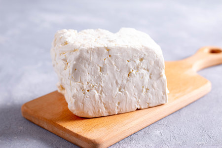Sliced fresh white cheese from cow's milk on a wooden cutting board