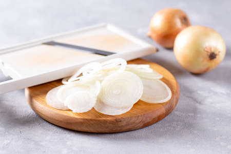Fresh chopped onions on wooden cutting board on a light concrete backgroundの写真素材