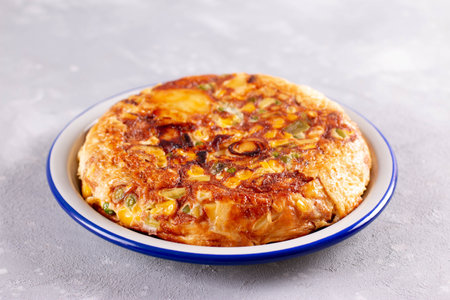 Delicious potato tortilla with vegetables with herbs on light backgroundの写真素材