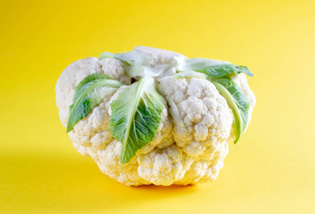 Cauliflower upside down on yellow background. Seasonal vegetables minimal style