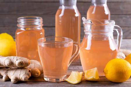 Kombucha or cider fermented drink. Cold tea beverage with beneficial bacteria, ginger, lemon on wooden background. For healthy nutrition.の写真素材