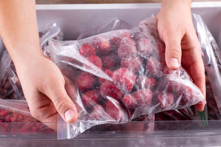 Frozen strawberries. Frozen berries and fruits in a plastic bag in freezerの写真素材