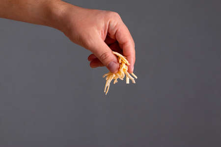 Closeup of man hand sprinkle grated cheese over dark backgroundの写真素材