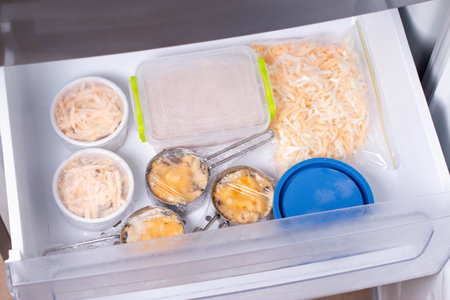 Frozen food in the freezer. Frozen Casserole, julienne. Mushroom, chicken and cheese gratin in bowls, container, bagsの写真素材