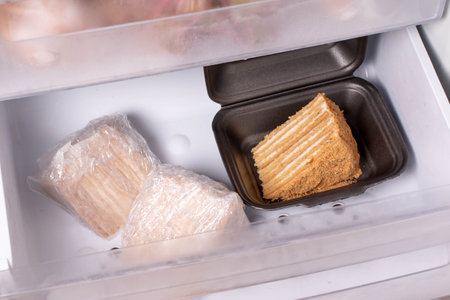Honey cake Medovik packed in cling film in the freezer. Frozen cakeの写真素材