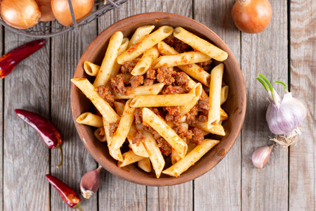 Penne pasta in tomato sauce with meat on wooden table. Top viewの写真素材