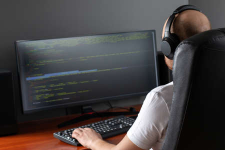 Program development concept. Young man working with computer at homeの写真素材