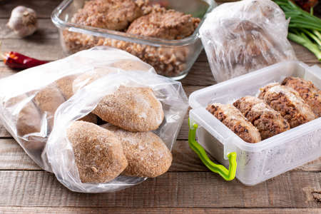 Frozen cutlets or meatballs in plastic bag on a wooden table, ready to eatの写真素材