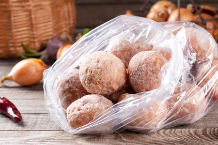 Plastic bags with frozen meat and meatballs in plastic bag on a wooden tableの写真素材