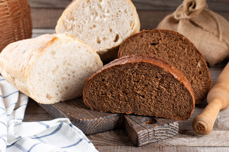 Rye bread and white wheat bread on cutting board. Whole grain rye bread with seeds on rustic...