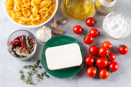Preparation of ingredients for feta pasta. Trending Feta bake pasta recipe made of cherry tomatoes, feta cheese, garlic and herbs on a light background. Top view, above, copy space.の写真素材