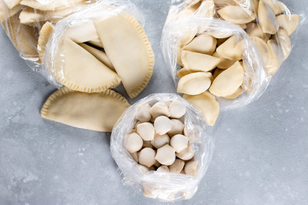 Frozen semi-finished products in the bag on gray table. Russian dumplings. Meat dumplings, ravioli....