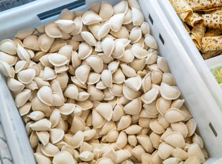 Frozen dumplings sold by weight in a refrigerator container on a store counter. Frozen food salesの写真素材