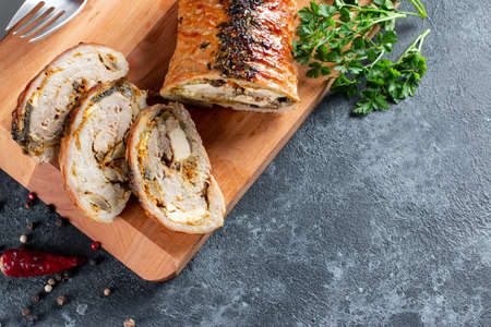 Overhead view of sliced roast pork roulade - Porchetta, delicious pork roast of Italian culinary holiday tradition on a stone background, flatlay, copy spaceの写真素材
