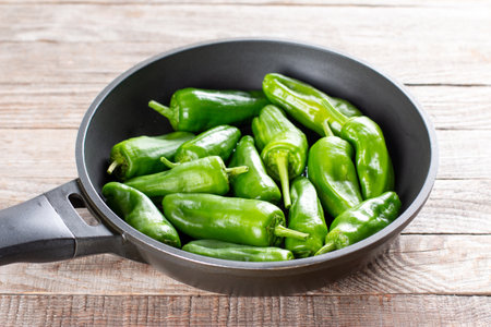 Fresh green pimientos or peppers de padron in frying pan. Fried in olive oil, and sprinkled with sea salt is a typical tapa meal in Spain. focus, narrow depth of fieldの写真素材