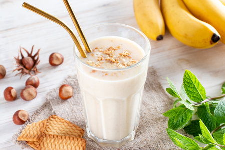 Delicious banana smoothie with sliced bananas and cookies in glass on a white background. Healthy breakfast.の写真素材