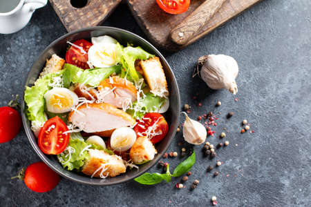 Caesar Salad with smoked chicken and parmesan on a plate on dark background. Top view, copy space.の写真素材