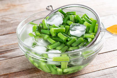Green beans in a colander. Boiled or blanched vegetables on a wooden tableの写真素材
