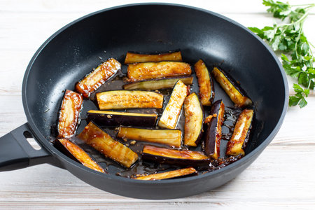 Fried eggplant dipped in honey in a frying pan. Delicious snackの写真素材