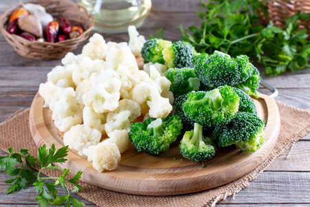 Frozen cauliflower and broccoli on a cutting board on a wooden tableの写真素材