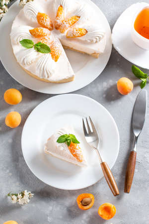 Portion of layered cheesecake with apricot on light background. Apricot tart. Fruit pie. French pastries.の写真素材